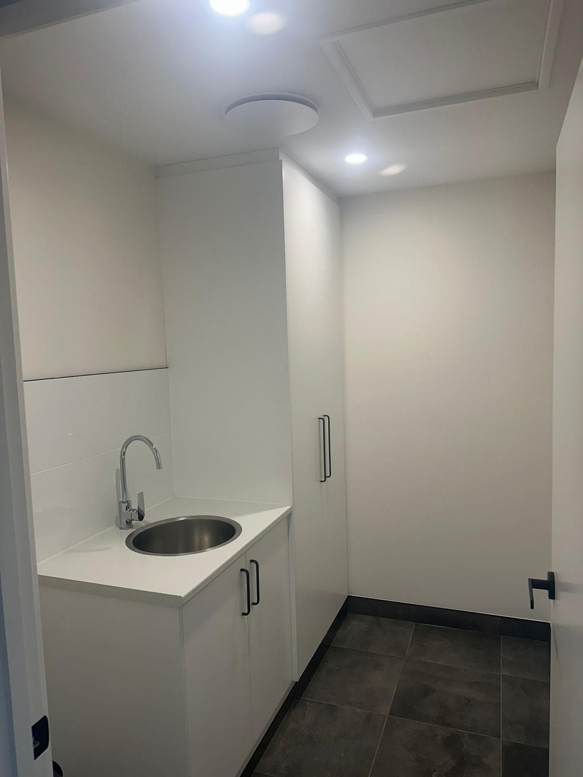 Freshly painted laundry with white walls and cabinetry